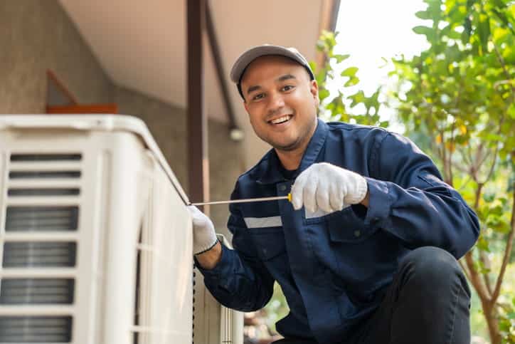 A HVAC technician working on an AC unit. 