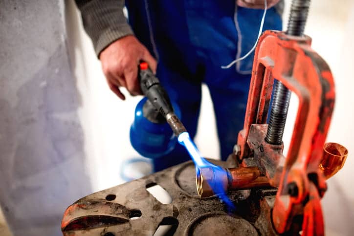 A plumber welding a pipe. 