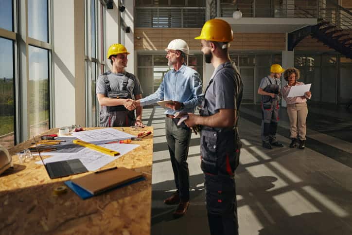 Five people are at a jobsite discussing construction plans on a project they are working on.