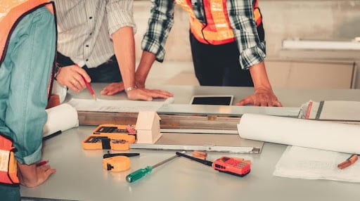 A project manager going over construction plans with his workers.
